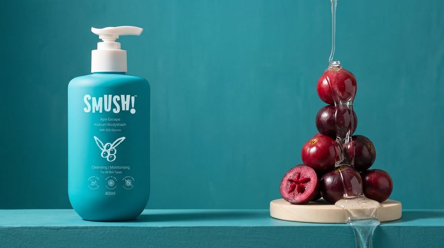 SMUSH! Ape Escape Kokum Body Wash, a teal pump bottle on a peacock-teal limewash ledge, with clear gel running down a stack of kokum fruit on a wooden round