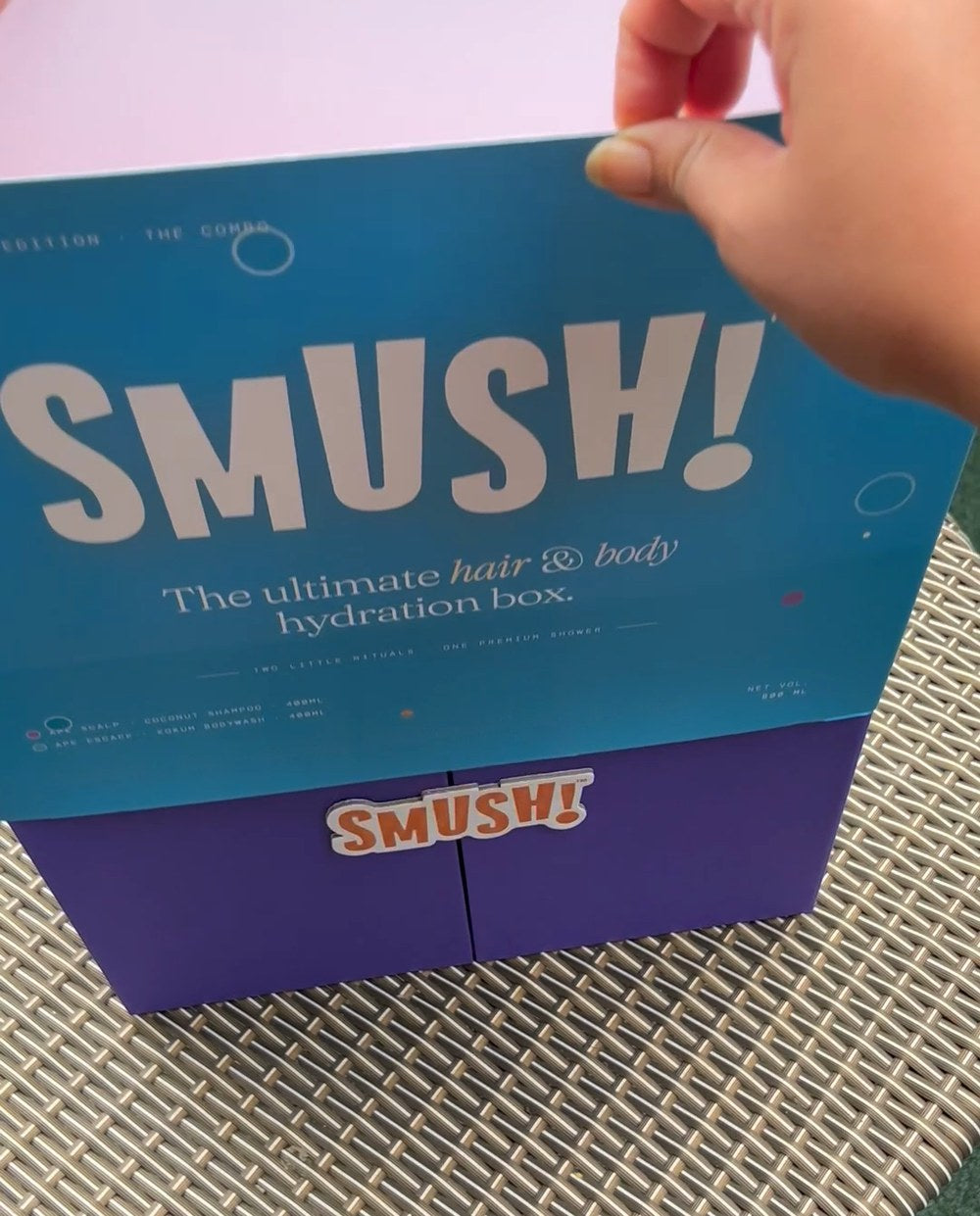 Hands slide the teal SMUSH! sleeve straight up off the gift box, the purple doors and the orange SMUSH! magnet showing underneath