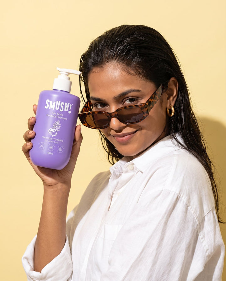 Woman in sunglasses holding Ape Scalp Coconut Shampoo