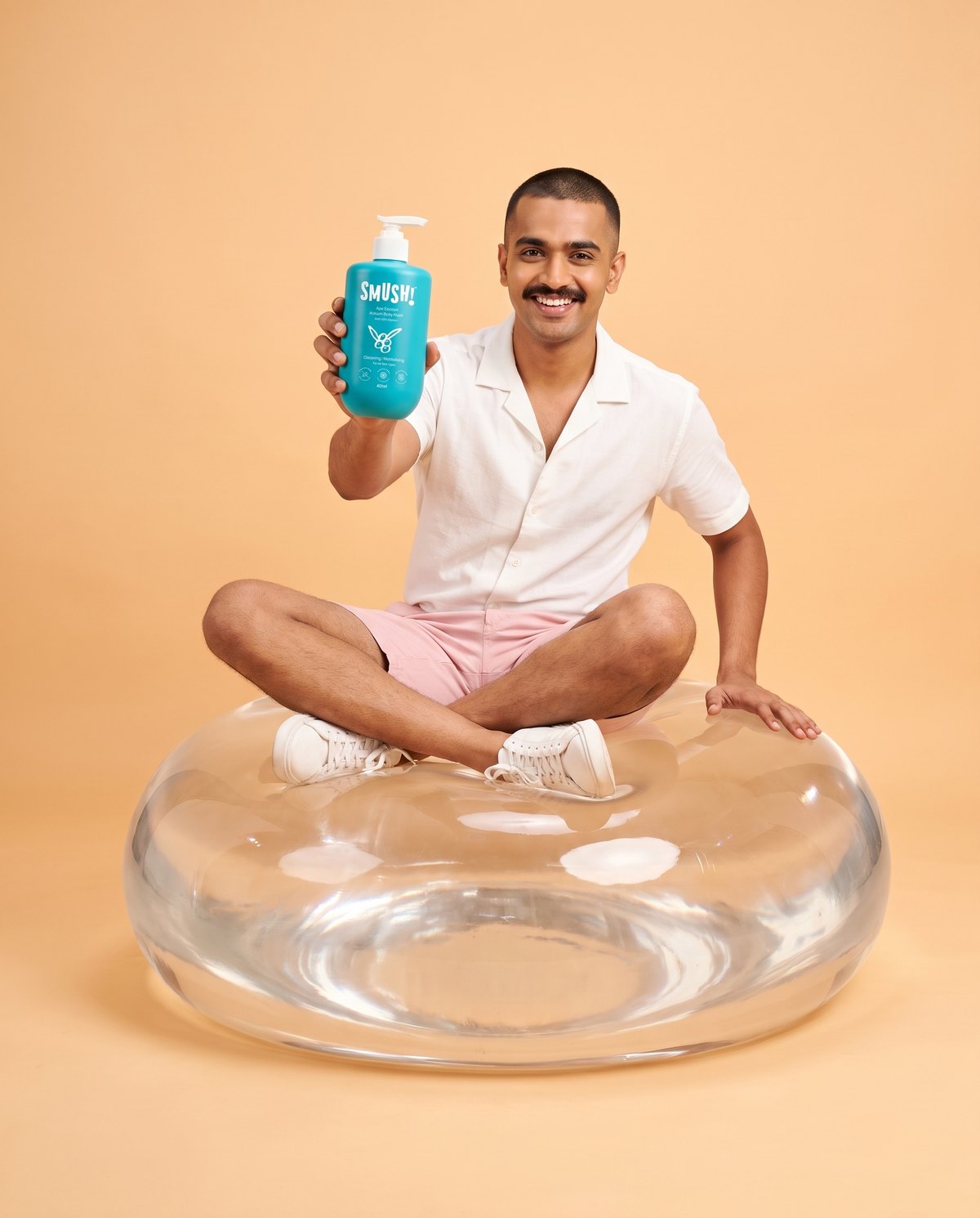 Man sitting on a giant clear float holding Ape Escape Kokum Body Wash