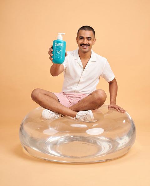 Man sitting on a giant clear float holding Ape Escape Kokum Body Wash