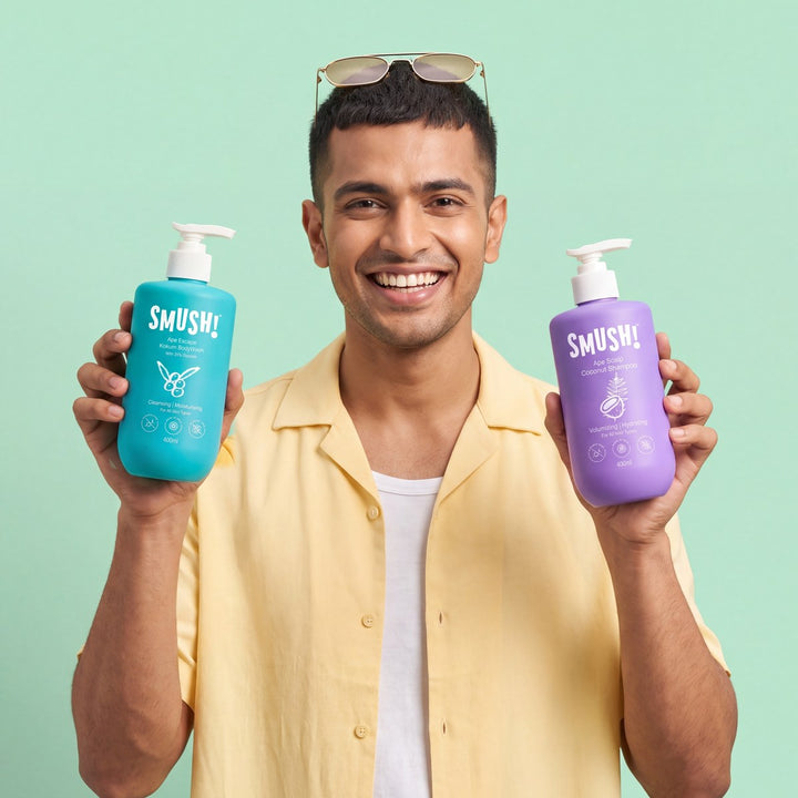 Man in a yellow shirt grinning, holding SMUSH! Ape Scalp Coconut Shampoo and Ape Escape Kokum Body Wash
