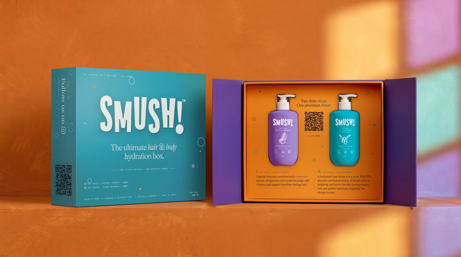 The SMUSH! gift box on a saffron ledge: on the left in its teal printed sleeve, on the right open, its purple doors swung out and the shampoo and the body wash standing in the orange tray