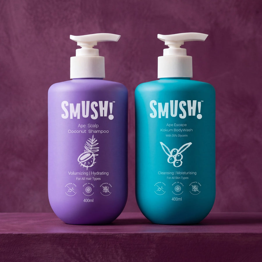 The two SMUSH! bottles side by side on a deep plum ledge: the purple Ape Scalp Coconut Shampoo and the teal Ape Escape Kokum Body Wash