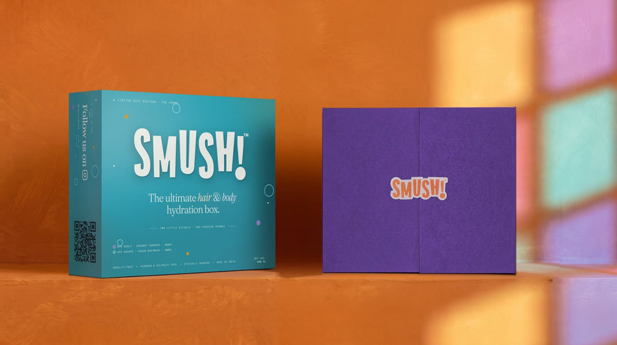 Two SMUSH! gift boxes on a saffron ledge in coloured window light: the left one in its teal printed sleeve, the right one closed, its purple doors sealed by the SMUSH! magnet