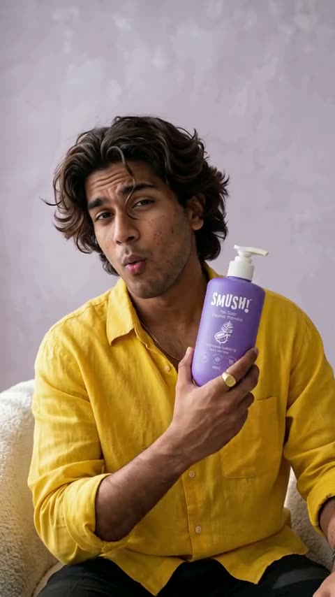 Video cover: A man in a yellow shirt sets the other bottles aside and holds up the purple SMUSH! Ape Scalp Coconut Shampoo