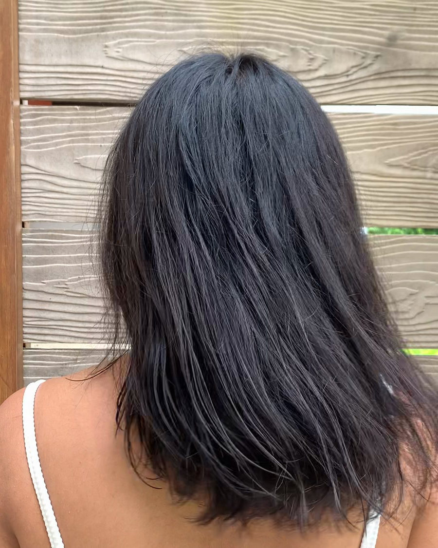 Smriti's hair from behind after a SMUSH! wash, soft and smooth past her shoulders, against a wooden fence