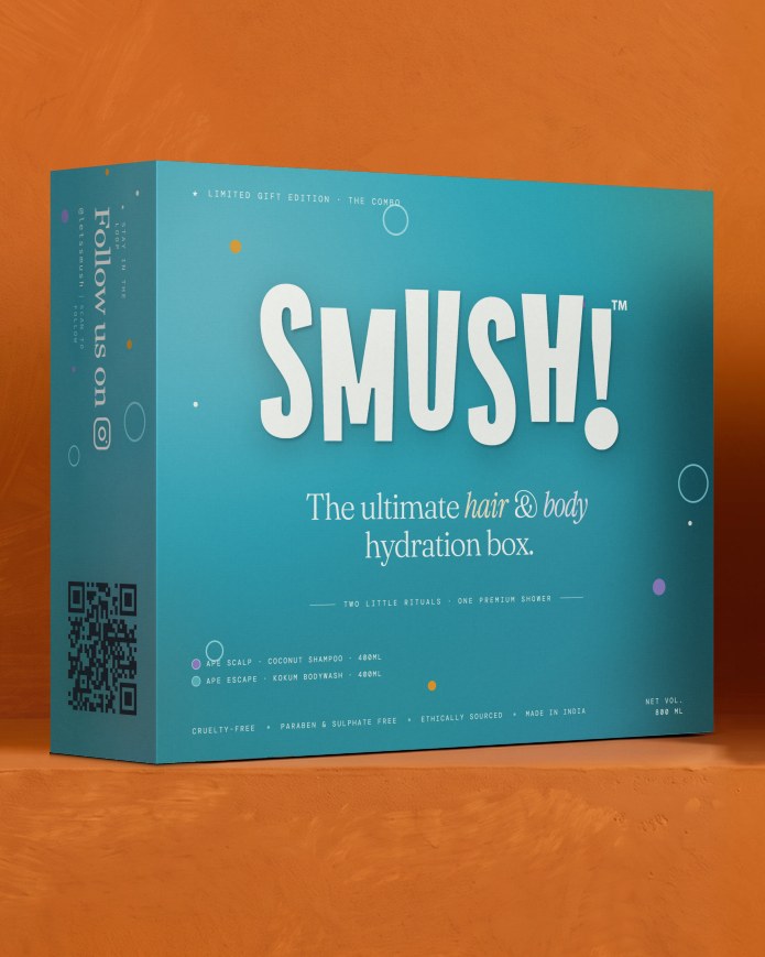 The SMUSH! gift box in its teal printed sleeve, the side panel reading Follow us on above a QR code, standing on a saffron ledge
