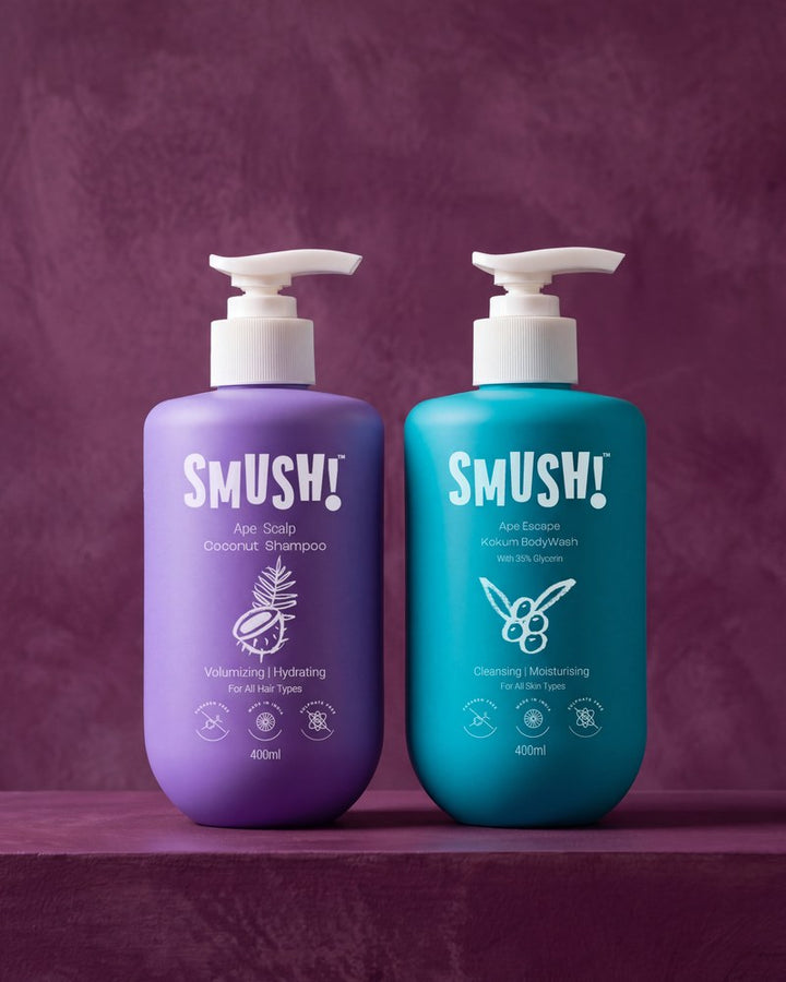 The coconut shampoo in its purple bottle and the kokum body wash in its teal bottle, side by side on a plum wall